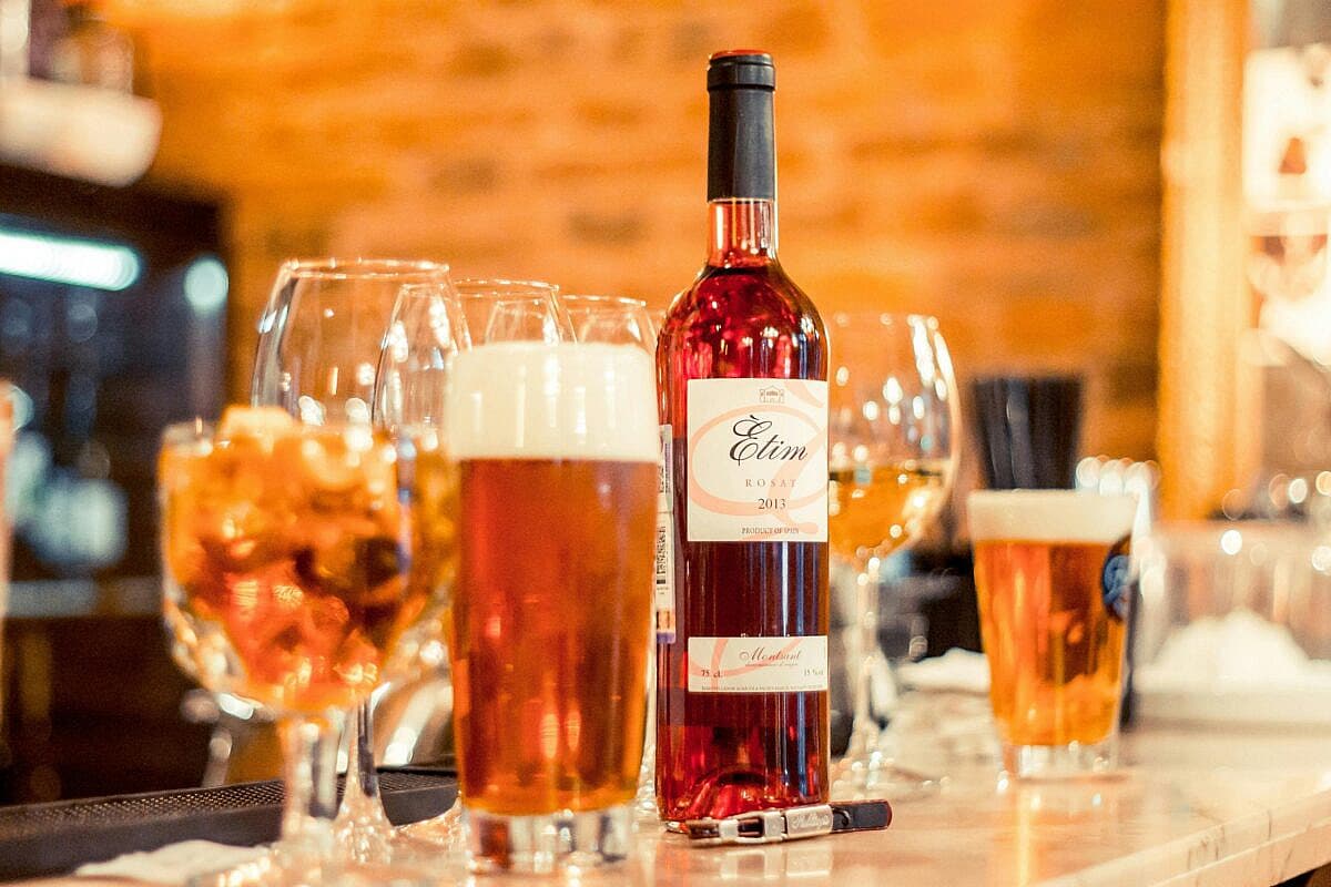 A bottle of wine and several glasses filled with wine on a table, alcoholic drinks are among the human foods toxic to dogs