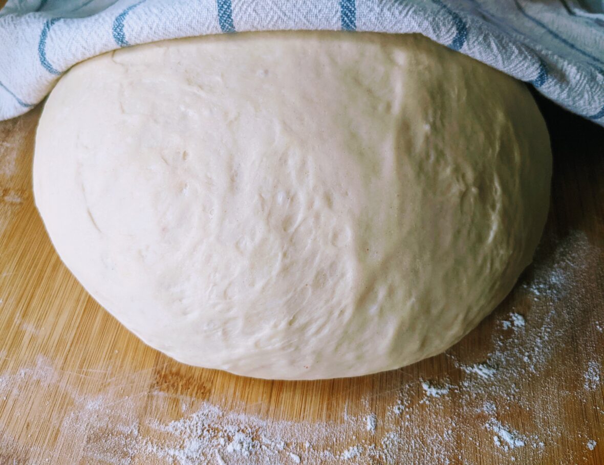 Close-up of risen bread dough slightly covered with a kitchen cloth, bread dough is among the human foods toxic to dogs